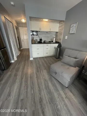 a living room with stainless steel appliances furniture and a wooden floor