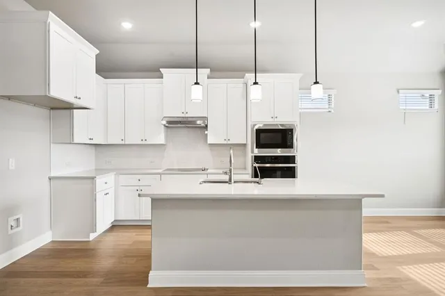 a kitchen with stainless steel appliances kitchen island a stove a sink and white cabinets