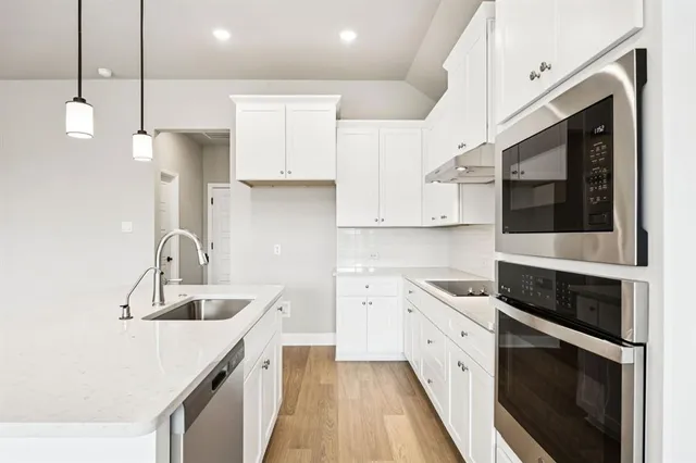 a kitchen with stainless steel appliances granite countertop a sink a stove and a refrigerator