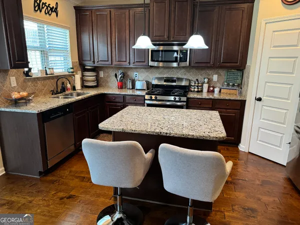 a kitchen with stainless steel appliances granite countertop a sink a stove a table and chairs