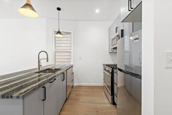 a kitchen with stainless steel appliances granite countertop a sink and a refrigerator
