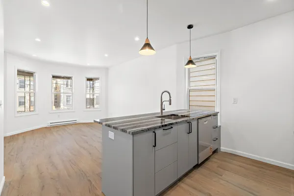 a kitchen with stainless steel appliances granite countertop a sink a window and wooden floor