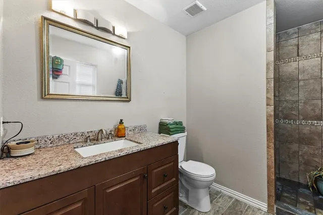a bathroom with a granite countertop toilet a sink and mirror