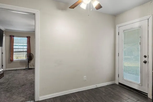 an empty room with wooden floor fan and windows