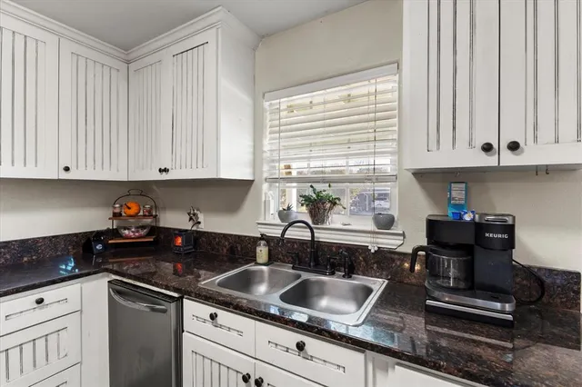 a kitchen with granite countertop a sink a stove and cabinets