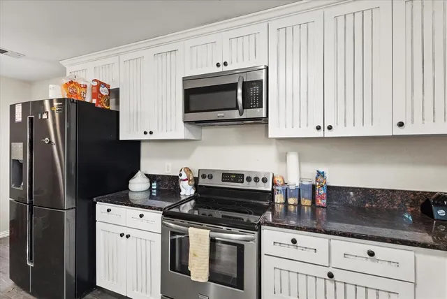 a kitchen with stainless steel appliances granite countertop a refrigerator stove and white cabinets
