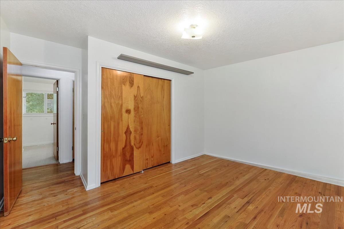 7141 West Hill Road Boise, ID 83714 - Photo 16 of 28 Room featuring wood-finish flooring, white walls, and two windows with blinds