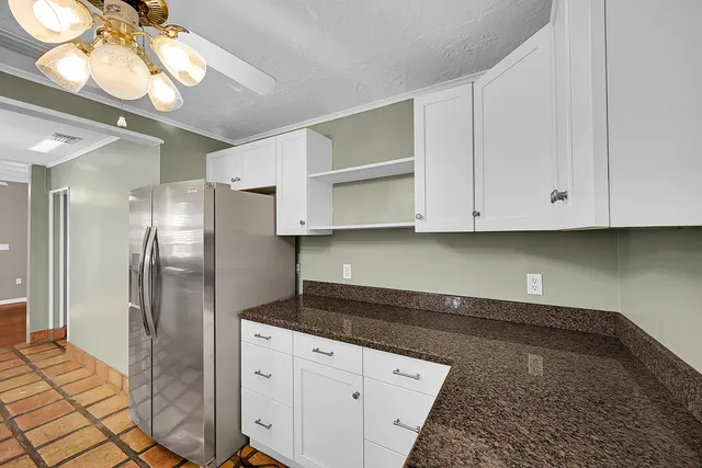 a kitchen with stainless steel appliances granite countertop a refrigerator a stove a microwave oven with white cabinets