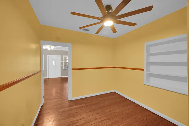 a view of a big room with wooden floor and a ceiling fan