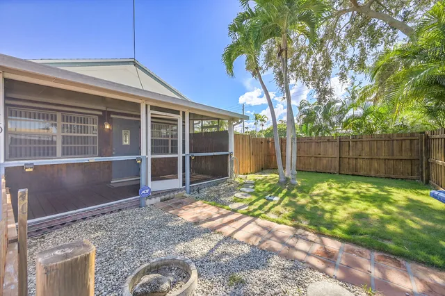 a view of a backyard with large trees and wooden fence