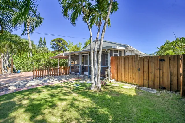 a view of a house with a small yard and a large tree