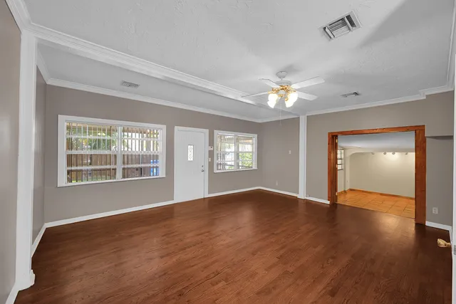 a view of an empty room with a window and wooden floor