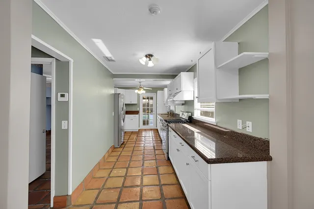 a large white kitchen with sink and stainless steel appliances