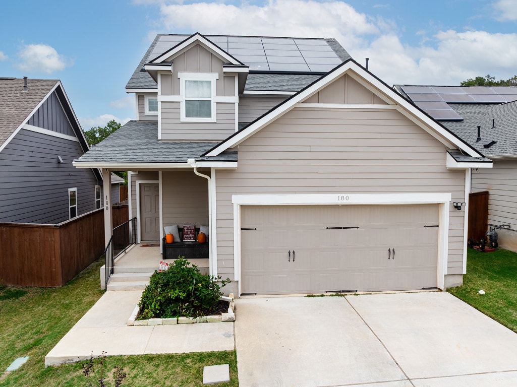 View of front of property with roof with shingles, board and batten siding, concrete driveway, and a porch