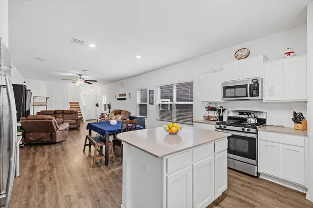 a kitchen with stainless steel appliances a refrigerator a stove a sink a dining table and chairs