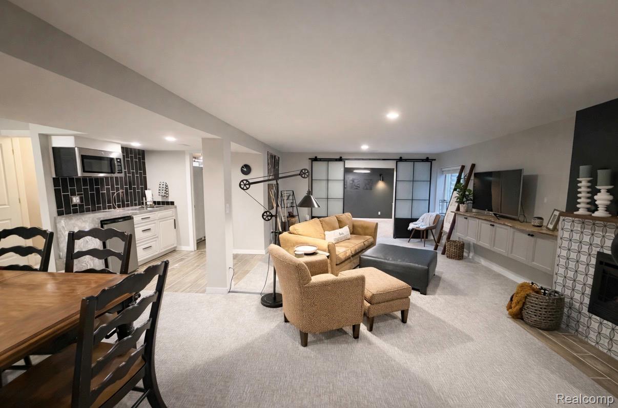 1876 Genoa Circle Howell, MI 48843 - Photo 20 of 36 Living area with a barn door, a glass covered fireplace, light colored carpet, and recessed lighting