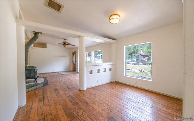 an empty room with wooden floor and windows