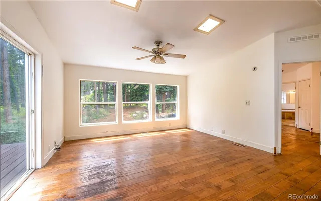 a view of an empty room with a window and wooden floor