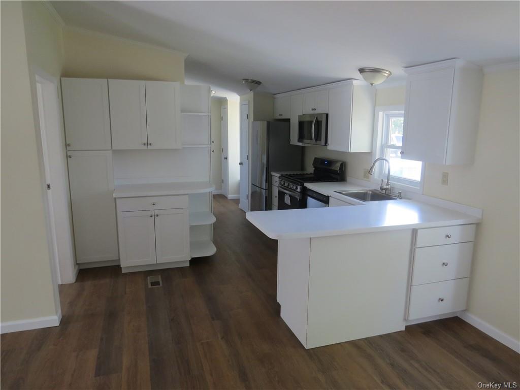 723 Beekman Road Hopewell Junction, NY 12533 - Photo 11 of 33 Kitchen with sink, kitchen peninsula, stainless steel appliances, white cabinets, and dark hardwood / wood-style floors