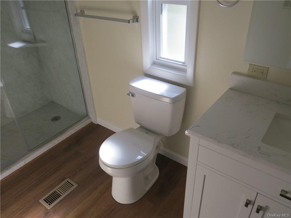 723 Beekman Road Hopewell Junction, NY 12533 - Photo 18 of 33 Bathroom featuring a shower with door, vanity, hardwood / wood-style floors, and toilet
