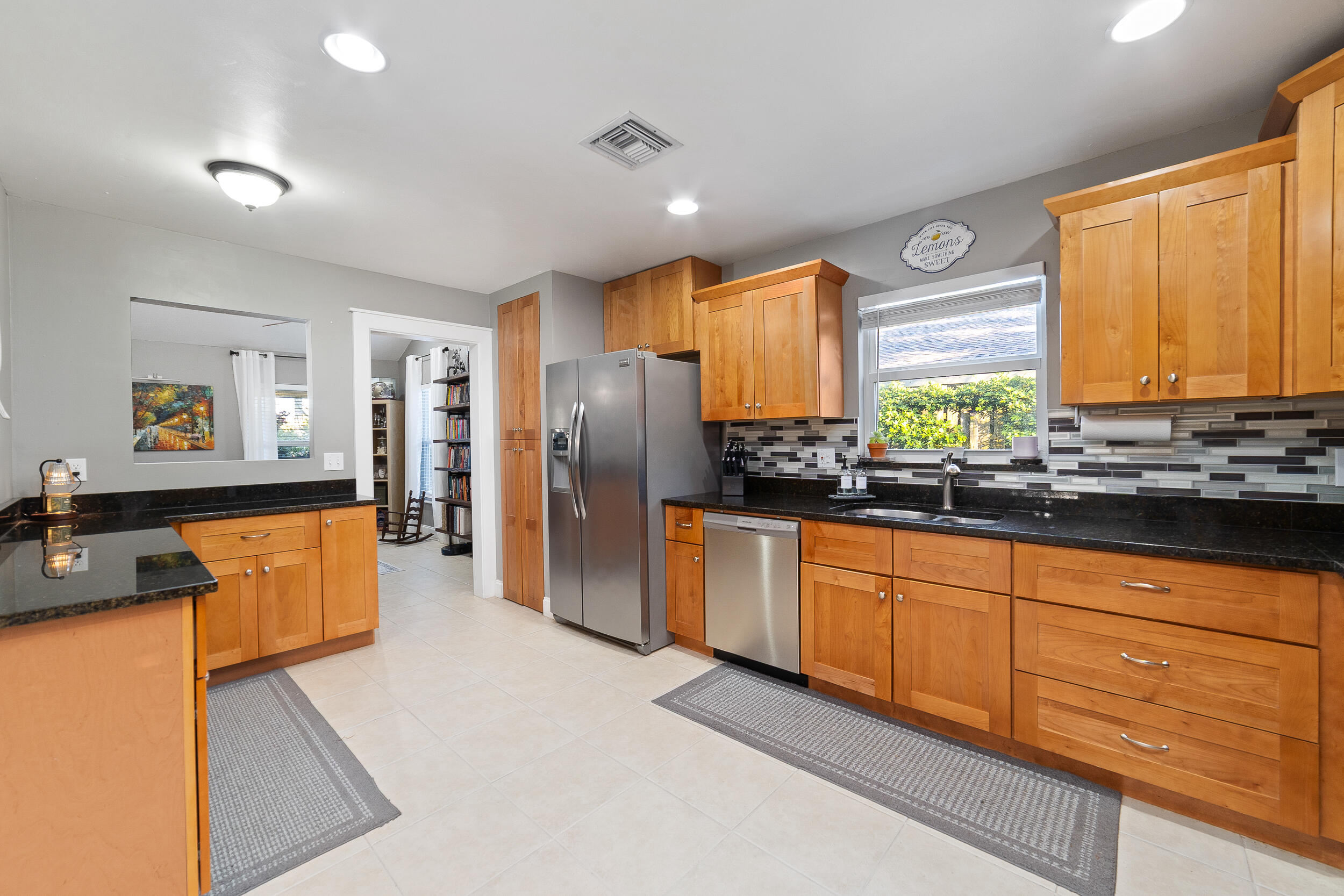 1045 Raintree Lane Wellington, FL 33414 - Photo 10 of 43 a large kitchen with stainless steel appliances a refrigerator a sink dishwasher a stove a dining table and chairs with wooden floor