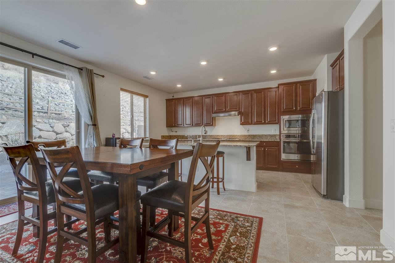 8845 Winter Peace Court Reno, NV 89523 - Photo 9 of 23 a kitchen with stainless steel appliances granite countertop a stove a sink a refrigerator with a dining table and chairs