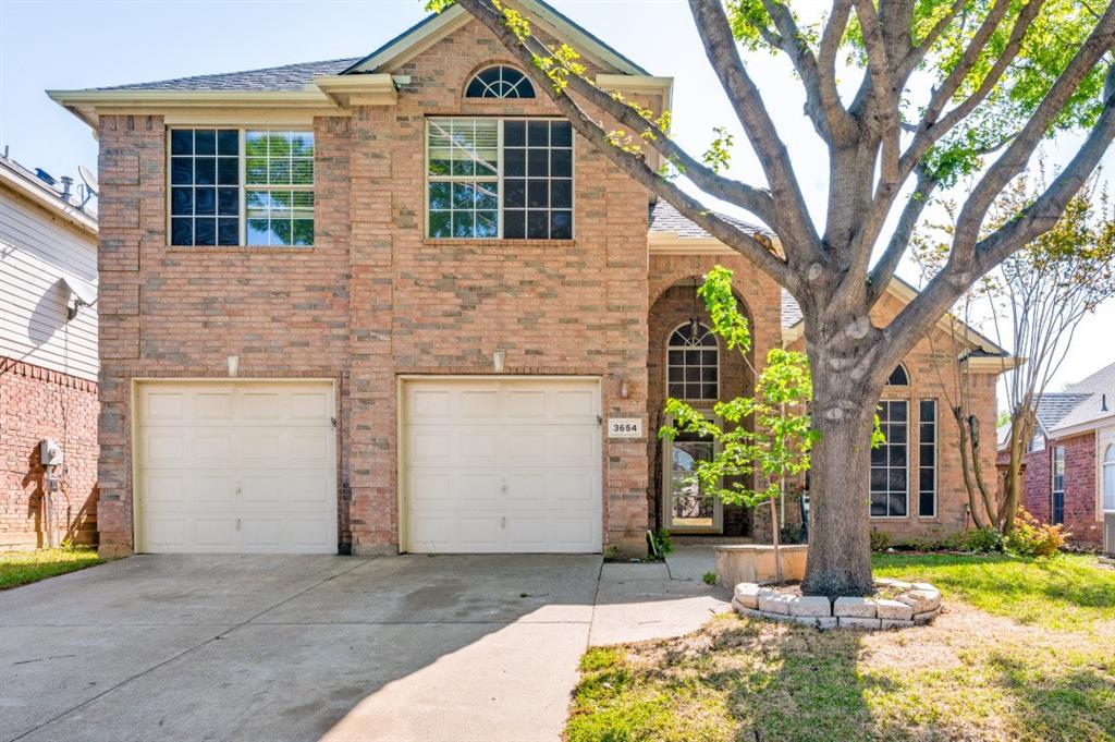 Traditional-style home with a garage, brick siding, driveway, and a shingled roof