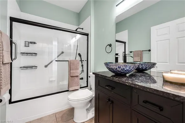 a bathroom with a granite countertop sink a toilet a mirror and shower