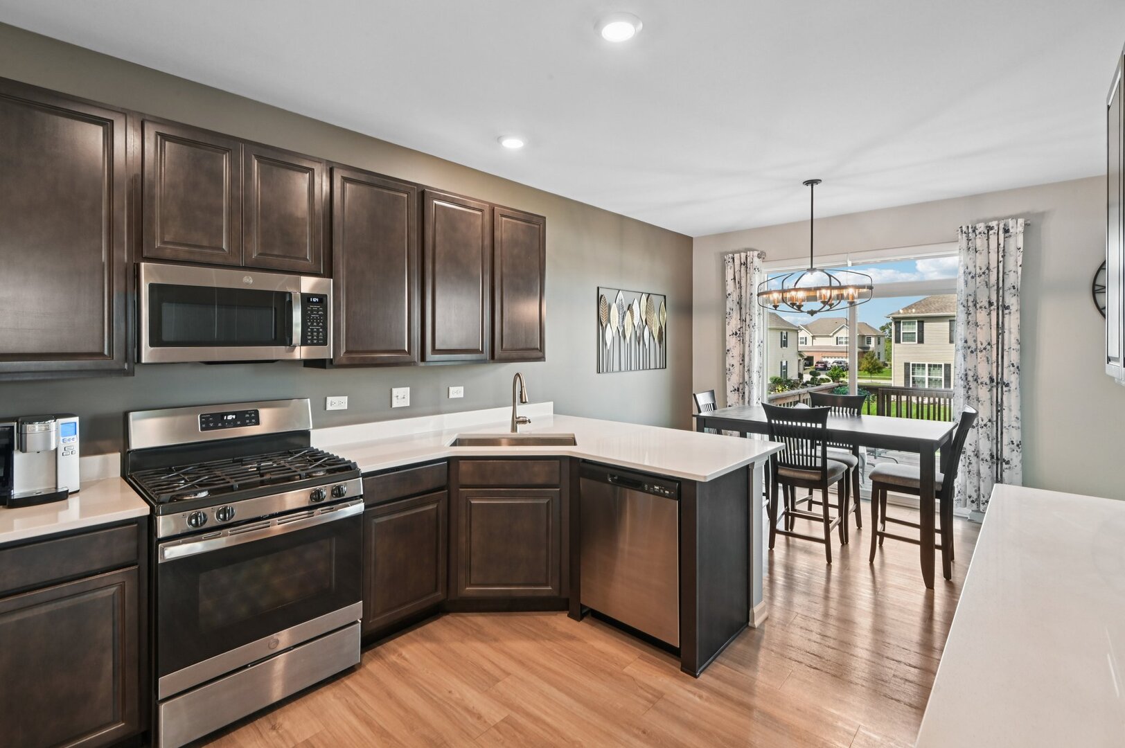 24734 South Dart Road Manhattan, IL 60442 - Photo 9 of 29 a kitchen with stainless steel appliances granite countertop a stove top oven a sink dishwasher a dining table and chairs with wooden floor