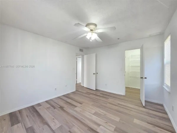 a view of a room with wooden floor and a ceiling fan