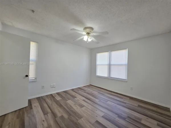 an empty room with a window and a ceiling fan