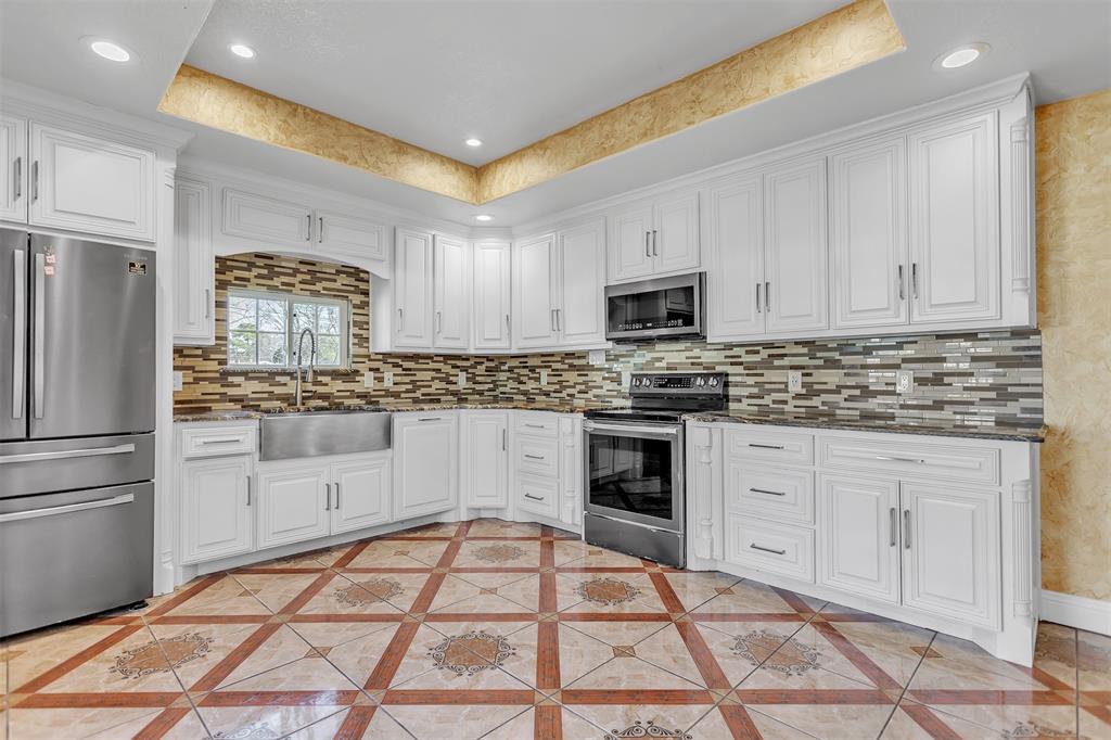 8115 Goldfield Drive Dallas, TX 75217 - Photo 14 of 16 a kitchen with granite countertop white cabinets and stainless steel appliances