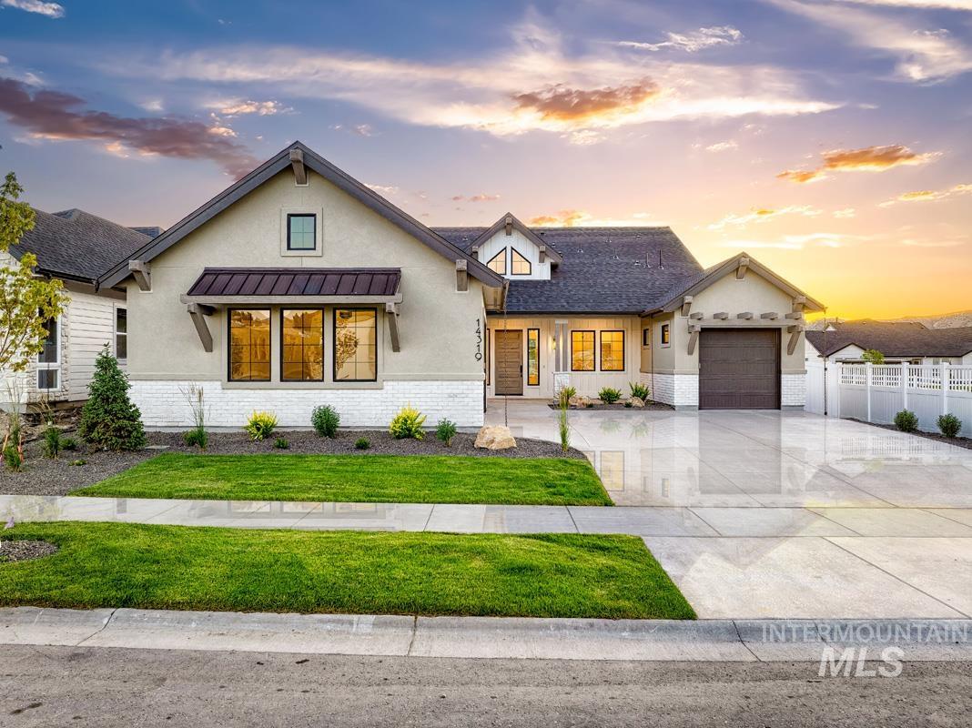 Modern farmhouse style home featuring stucco siding, driveway, brick siding, a garage, and a standing seam roof