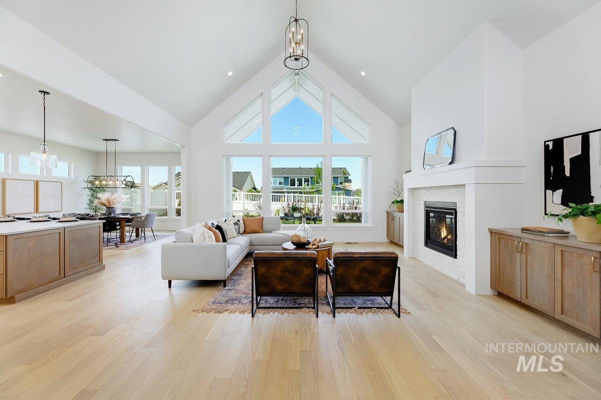 13265 North Spring Creek Way Boise, ID 83714 - Photo 3 of 35 Living area featuring a chandelier, a high ceiling, a glass covered fireplace, and light wood-style flooring