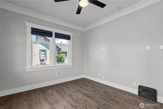 an empty room with wooden floor chandelier fan and windows