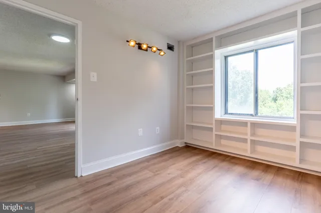 an empty room with wooden floor and windows