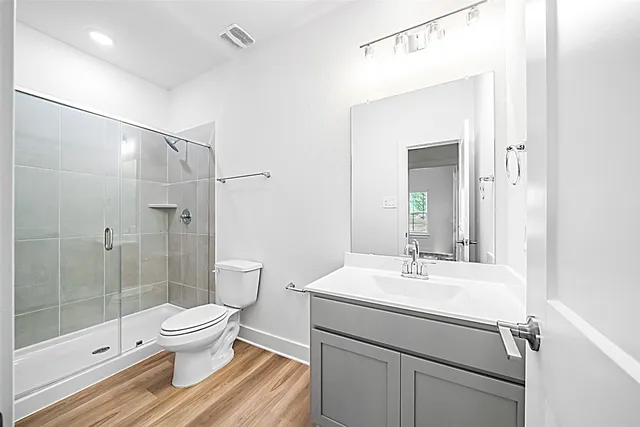 a spacious bedroom with a bed a mirror on dresser and a chandelier