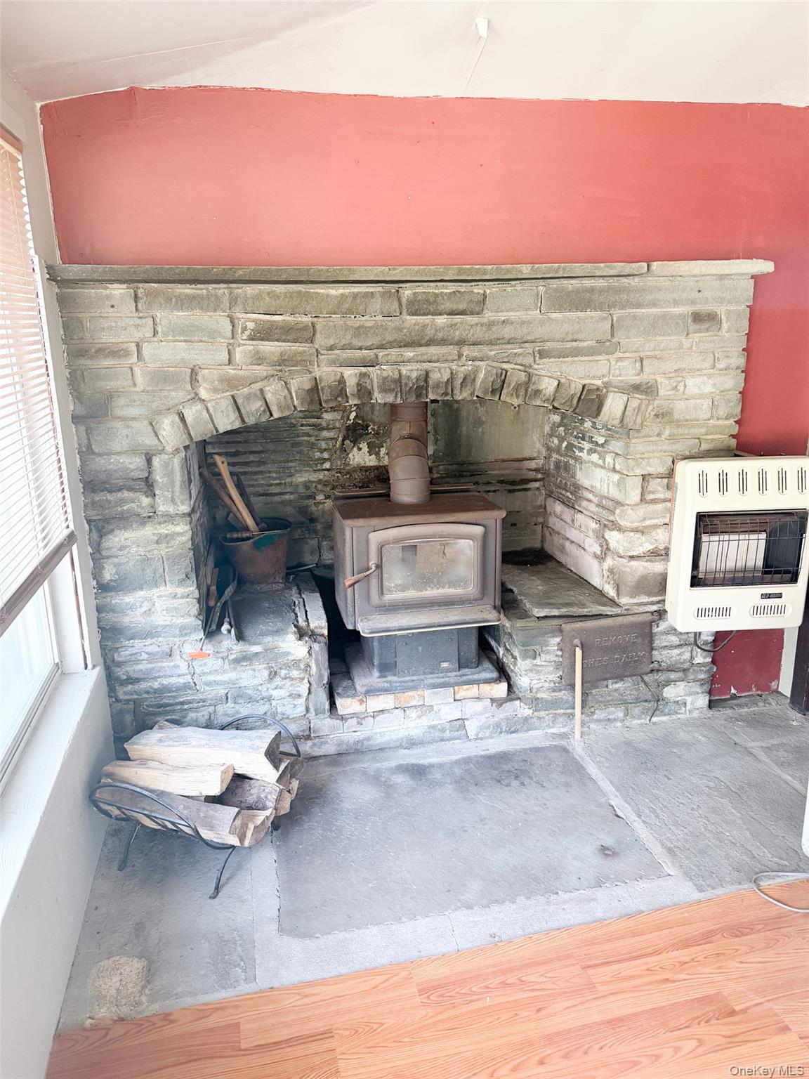 77 Rockland Road Roscoe, NY 12776 - Photo 10 of 20 Stone fireplace with a wood-burning stove insert, an arched firebox, and a stone hearth