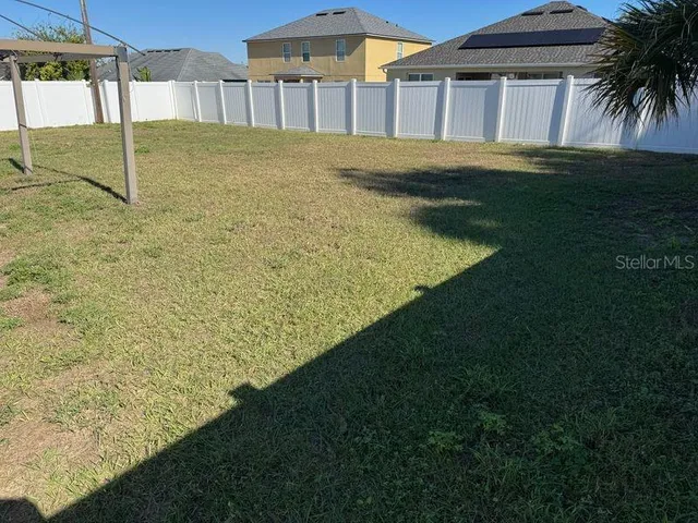 a view of a white house next to a yard and road