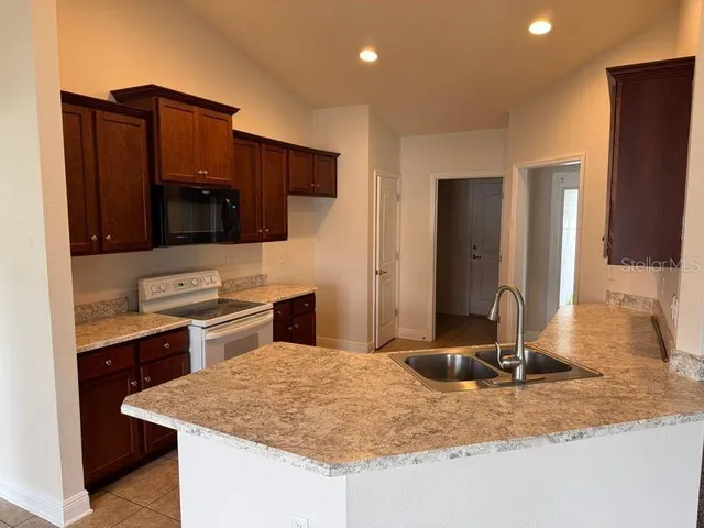 a kitchen with stainless steel appliances kitchen island granite countertop a sink stove and refrigerator