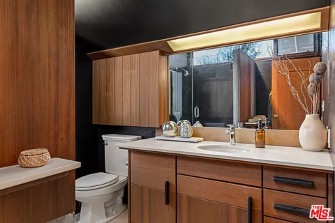 a bathroom with a granite countertop sink toilet and a mirror