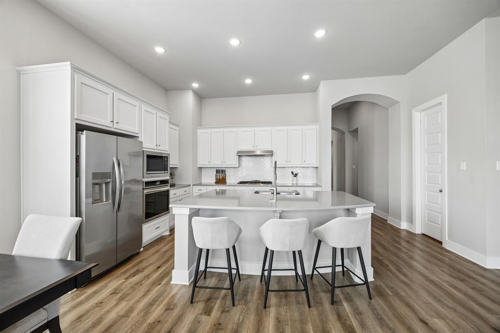 2430 Brightling Bend Forney, TX 75126 - Photo 15 of 37 Kitchen featuring stainless steel appliances, dark wood-style flooring, white cabinets, recessed lighting, and tasteful backsplash