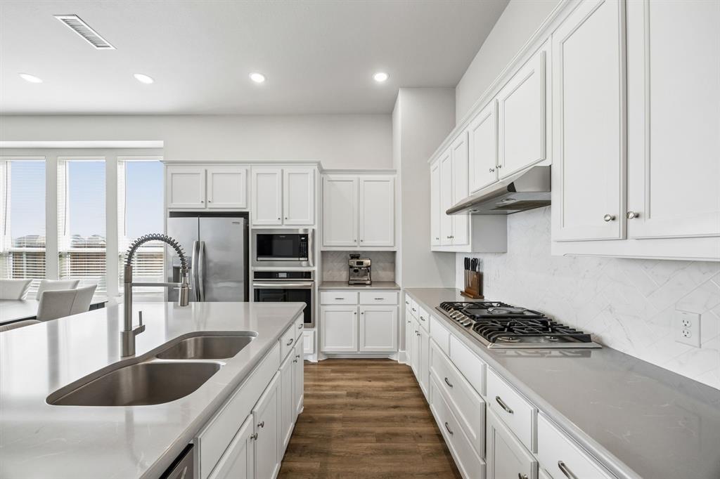 2430 Brightling Bend Forney, TX 75126 - Photo 16 of 37 Kitchen featuring stainless steel appliances, dark wood-style flooring, white cabinets, recessed lighting, and tasteful backsplash