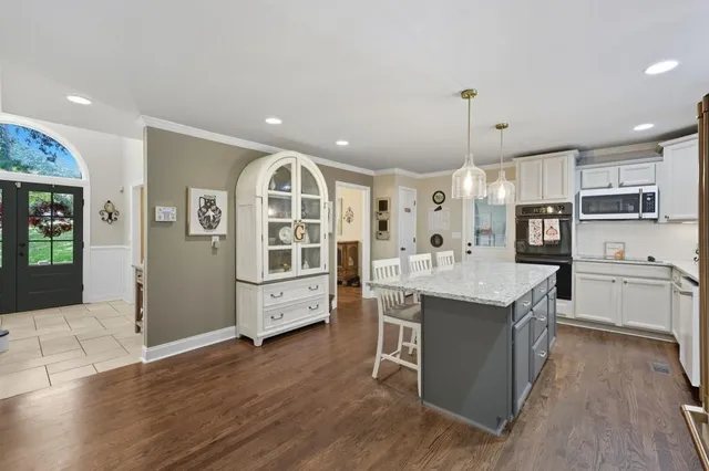 a large kitchen with stainless steel appliances kitchen island granite countertop a lot of cabinets and wooden floor