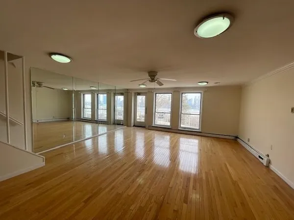 a view of empty room with wooden floor and fan