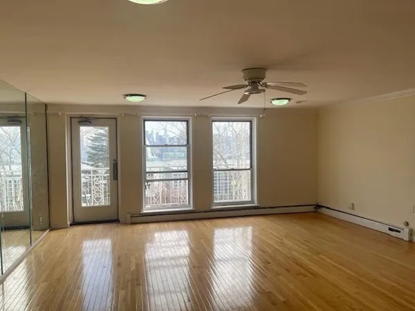 a view of an empty room with a window and wooden floor