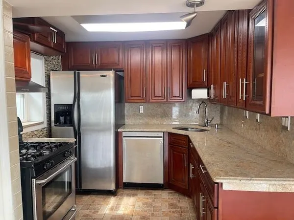 a kitchen with stainless steel appliances granite countertop wooden cabinets a sink and a stove