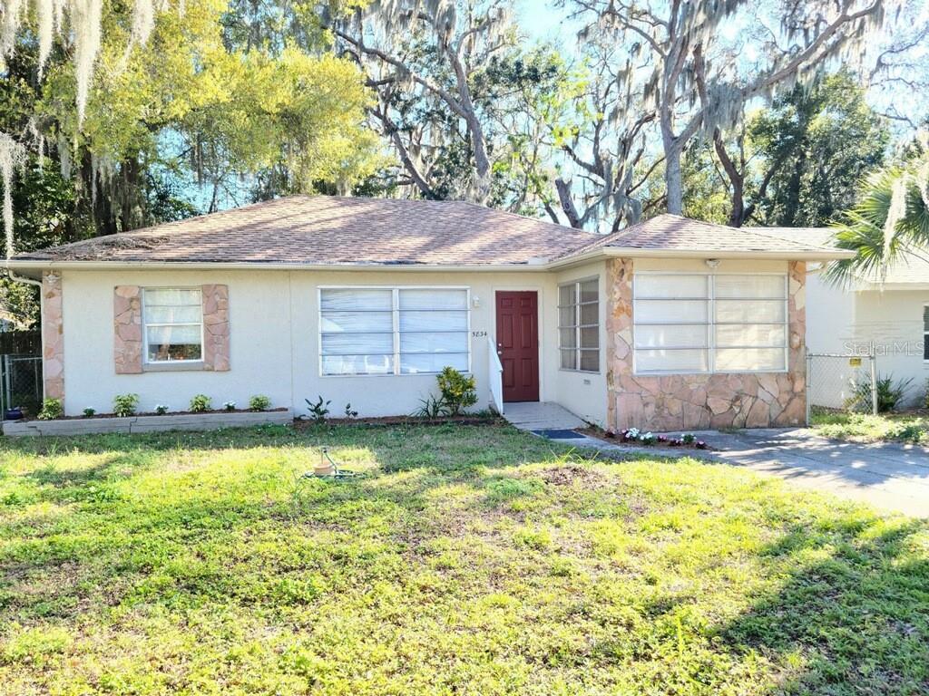 a view of a house with a yard and large tree