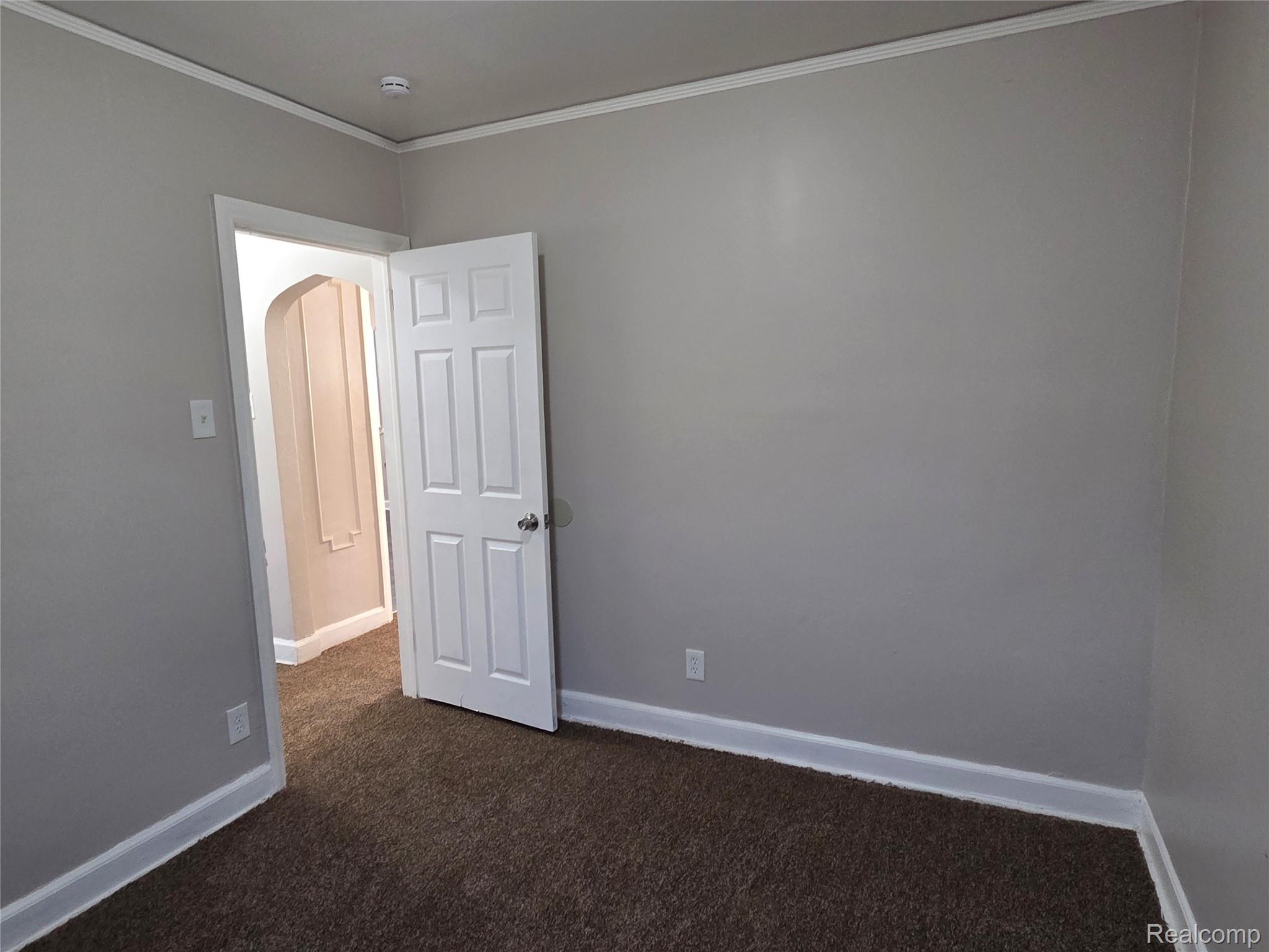 5274 Nottingham Road Detroit, MI 48224 - Photo 9 of 22 Spare room with arched walkways, dark carpet, and ornamental molding