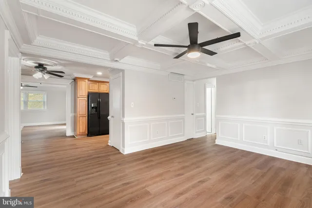 a view of an empty room with wooden floor ceiling fan